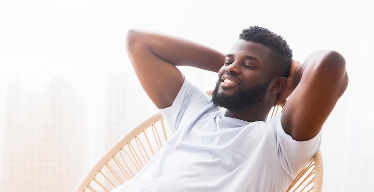 relaxed-african-american-man-with-beard-sits-wicker-chair-with-his-arms-his-head_922936-53847